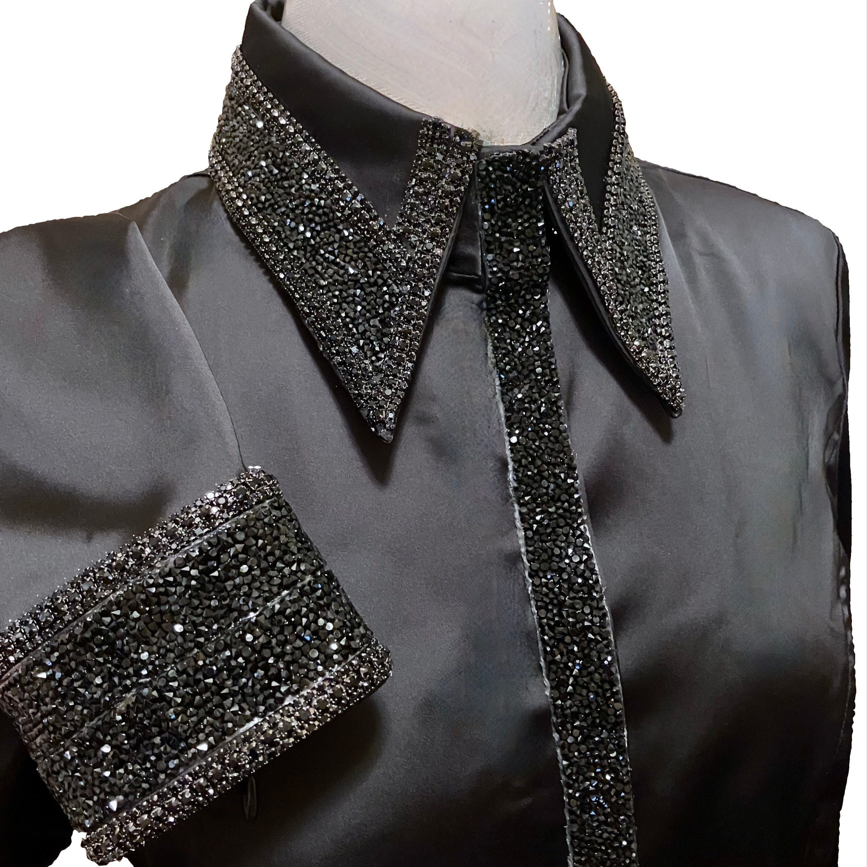 Black blouse with sparkling collar and cuffs on a mannequin against a white background